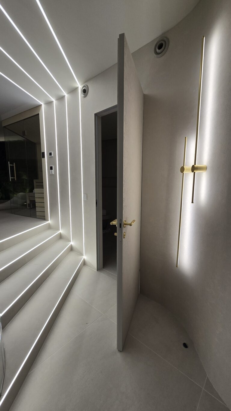 Otwarte drzwi ukryte na wymiar w luksusowym korytarzu z oświetleniem LED – kompleksowa realizacja Magara Indoors.