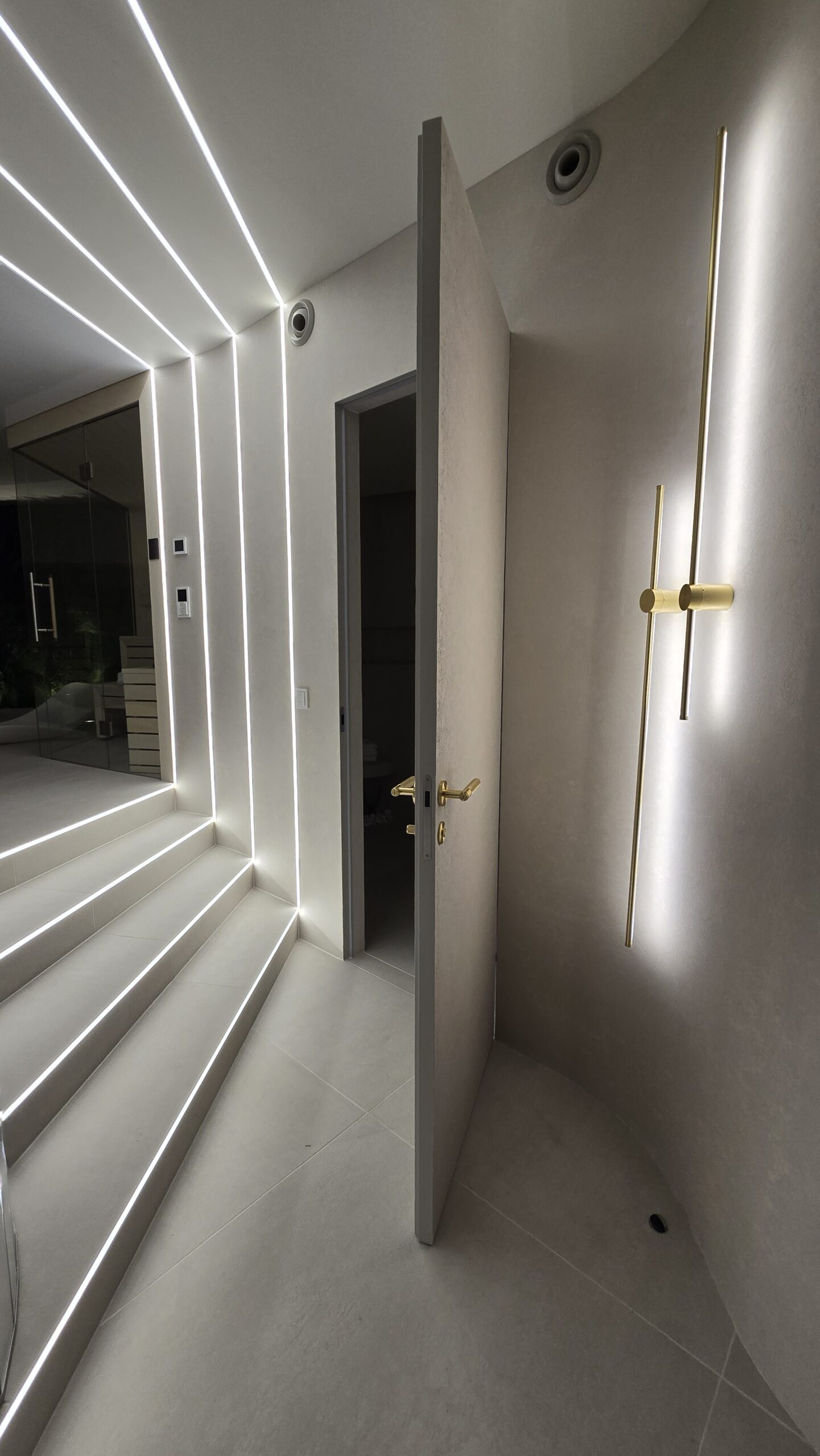 Otwarte drzwi ukryte na wymiar w luksusowym korytarzu z oświetleniem LED – kompleksowa realizacja Magara Indoors.